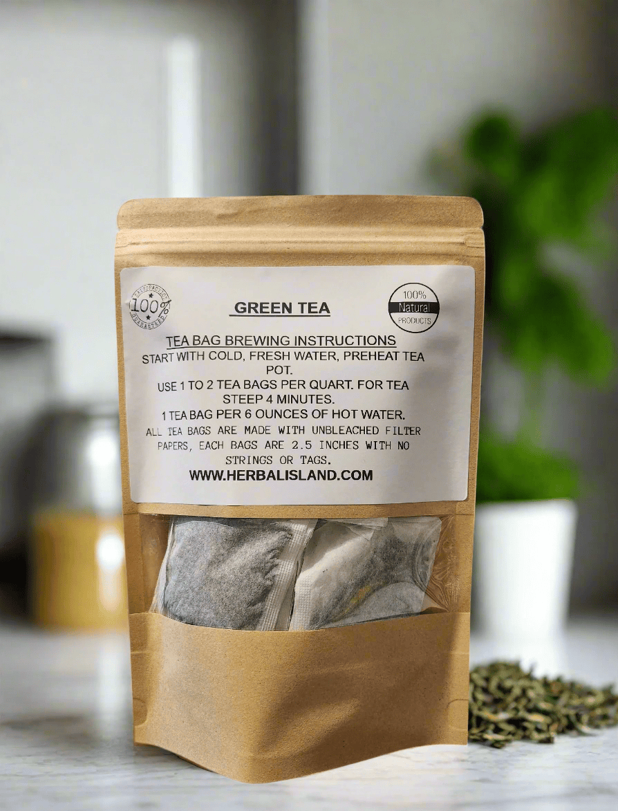 Herbal Island green tea bags stacked in a clear box with green tea leaves in the background, ready for brewing.